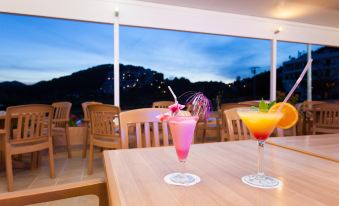 two glasses of colorful drinks are on a table in front of a table with chairs at Typic Oasis Sa Tanca