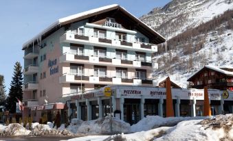 "a large hotel building with a sign that reads "" royal hotel "" is surrounded by snow - covered mountains" at Matterhorn Inn