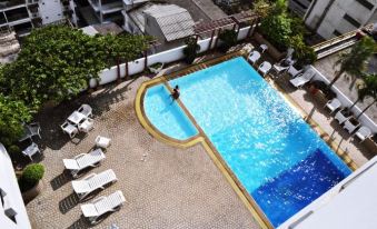 An overhead view reveals a spacious ground floor area with a large swimming pool surrounded by chairs and tables at Baiyoke Suite Hotel