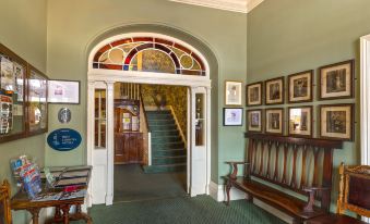 a staircase leads to a door with stained glass windows , and a bench in the foreground at Londonderry Arms Hotel