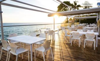 a wooden deck overlooking the ocean , with several tables and chairs set up for outdoor dining at Acantilados