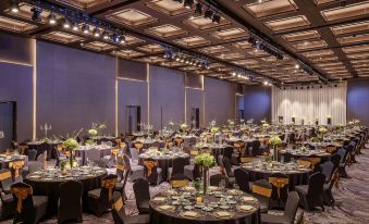 a large banquet hall filled with round tables and chairs , ready for a formal event at Lotte Hotel Yangon