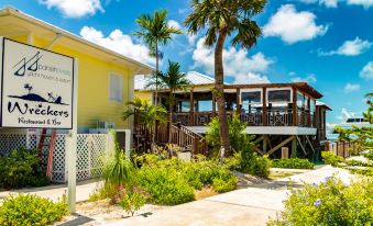 a yellow building with a balcony and palm trees , surrounded by greenery and a white fence at Spanish Wells Yacht Haven