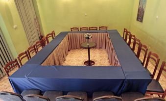 a conference room with a table covered in a blue cloth and chairs arranged around it at Hotel Regency