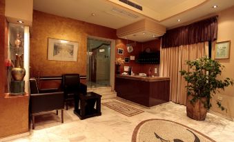 a luxurious hotel lobby with marble floors , wooden furniture , and a large reception desk , as well as a coffee table and potted plant at Hotel Regency