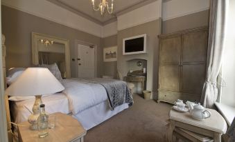 a large bedroom with a king - sized bed , a fireplace , and a tv mounted on the wall at St Andrews Town Hotel