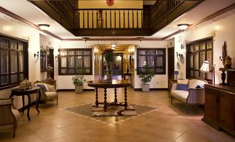 a spacious hotel lobby with hardwood floors , a large round table in the center , and several chairs surrounding it at San Juan Hotel