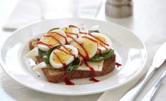 a plate of toast topped with eggs , tomatoes , and cheese , sitting on a dining table at Residence Inn Waynesboro