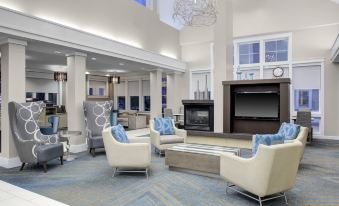 a spacious living room with white and blue furniture , including couches , chairs , and a fireplace at Residence Inn Richmond Chester