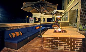a brick patio with a fire pit , several couches , and an umbrella , creating an inviting outdoor seating area at SpringHill Suites Deadwood