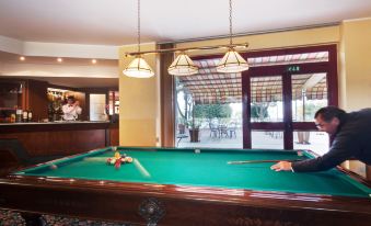 a man is playing a game of pool in a room with a bar and window at Hotel Marina
