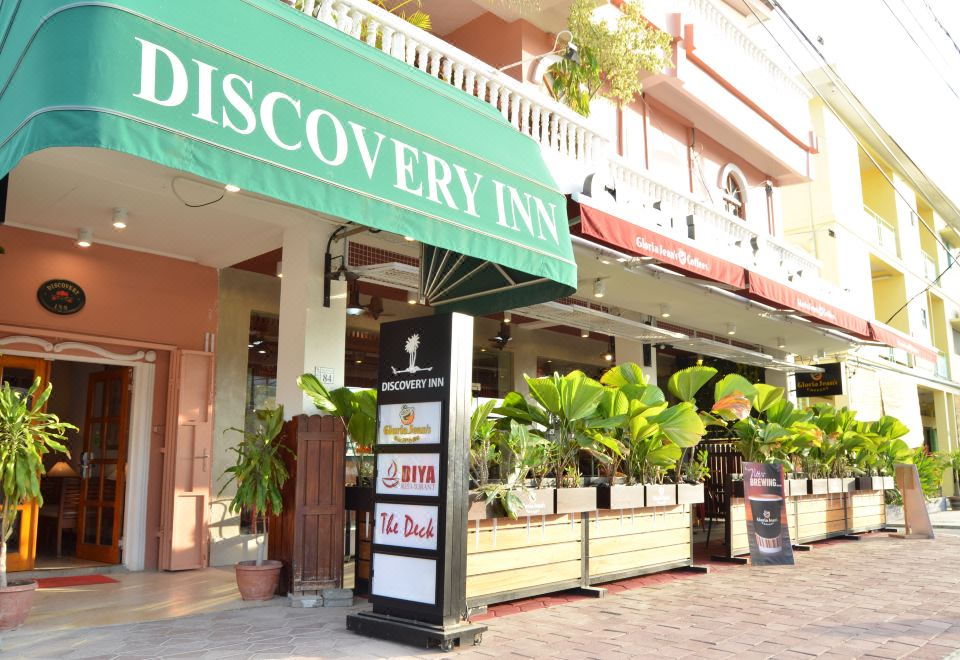 "the entrance to a building with a sign that reads "" discovery inn "" and several potted plants on the sidewalk" at Discovery Inn