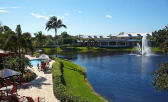 a resort with a large body of water , surrounded by lush green grass and trees , as well as a fountain in the foreground at Inn at Pelican Bay