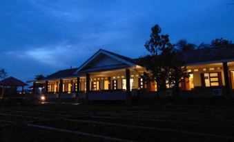 a large white building , possibly a train station , illuminated at night with the sun setting in the background at Wisma BPI