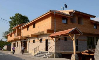 a large wooden building with a red tile roof , situated next to a dirt road at Alfa Hotel