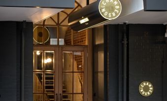 a modern building entrance with a wooden door and stairs leading up to it , illuminated by small lights at The Chamberson