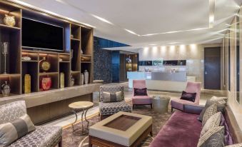 a modern hotel lobby with various seating options , including couches and chairs , as well as a television at Gambaro Hotel Brisbane