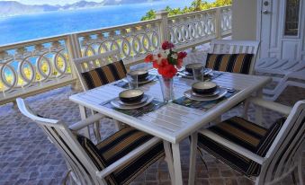 a dining table set for a meal on a balcony overlooking the ocean , with a view of the water at Ocean View Villas
