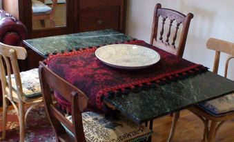 a dining table with a red and black floral tablecloth , surrounded by chairs , is set for two people at Albury Cottages
