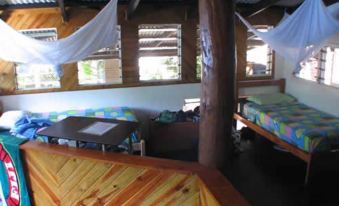 a room with wooden walls and ceiling , featuring bunk beds , a dining table , and several chairs at Safari Lodge