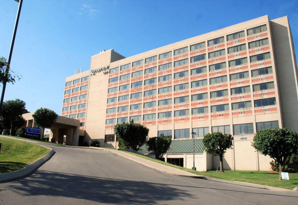 a large hotel building situated on a city street , with a car parked in front of it at Riverview Inn