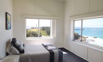 a modern bedroom with a large window offering a view of the ocean , white walls , and black carpet at Pacific Hotel Yamba