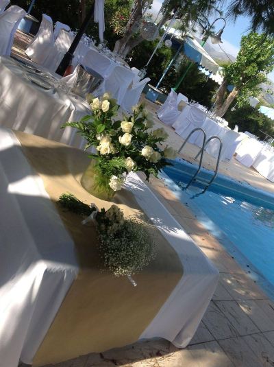 a white table with a vase of flowers in the middle is set up near a swimming pool at Hotel Summery