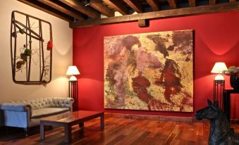 a large red painting is displayed on a red wall in a room with wooden floors and furniture at Hotel El Rancho