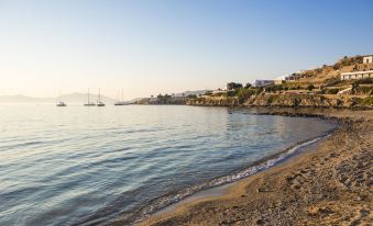 a serene beach scene with a group of people enjoying their time on the sandy shore at Mykonos Beach Hotel