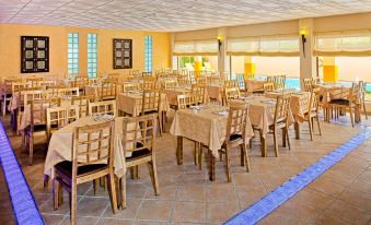 a large dining room with multiple tables and chairs , all set for a meal , is decorated with a blue ceiling and walls at Casablanca Unique Hotel