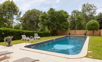 a large swimming pool surrounded by green grass and trees , with several lounge chairs placed around it at Hôtel Saint-Martin - la Maison Younan