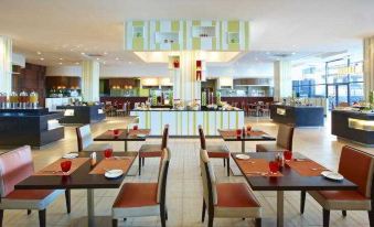 The restaurant has tables and chairs in the center area, as well as in other seating areas at Four Points by Sheraton Kuching