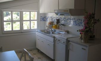 a kitchen with white cabinets , blue and white tile backsplash , sink , dishwasher , oven , and refrigerator at Villa Margherita