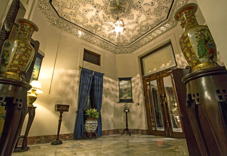 a luxurious hotel lobby with a marble floor , gold trim , and ornate ceiling , decorated with blue curtains , plants , and chandeliers at Faisalabad Serena Hotel