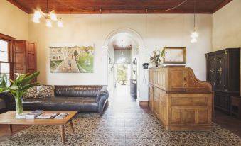 a cozy living room with a wooden table , a leather couch , and a fireplace , as well as a doorway leading to another room at Schoone Oordt Country House