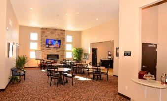 a large dining room with multiple tables and chairs , a television mounted on the wall , and a pool table in the background at Cobblestone Inn & Suites - Holstein