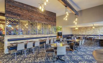 a modern restaurant with wooden tables , chairs , and a large window , giving it an elegant and inviting atmosphere at Mercure Warragul