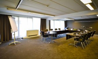 a large conference room with multiple chairs arranged in rows and a projector on the wall at Fletcher Hotel Restaurant Loosdrecht-Amsterdam