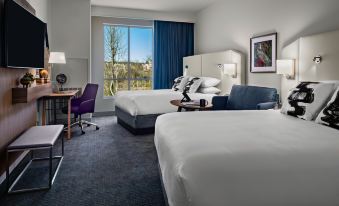 a modern hotel room with two beds , a desk , and a window offering a view of the city at Crowne Plaza North Augusta