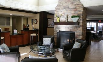 a living room with a fireplace , leather chairs , and a tv . also a dining table in the room at Sonesta ES Suites San Francisco Airport San Bruno