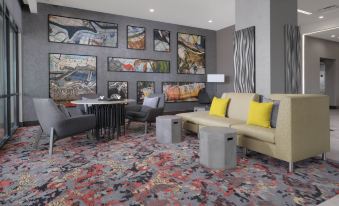 a modern living room with a large couch , coffee table , and paintings on the wall at Courtyard Austin Pflugerville and Pflugerville Conference Center