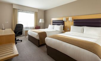 a hotel room with two beds , a window , and a chair , all neatly arranged on a carpeted floor at Holiday Inn London - Brentford Lock