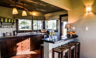 a well - equipped kitchen with wooden cabinets , a dining table , and several stools for seating guests at Santa Virginia