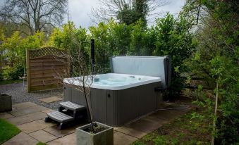 a backyard with a hot tub surrounded by lush greenery , creating a serene and relaxing atmosphere at The Snug