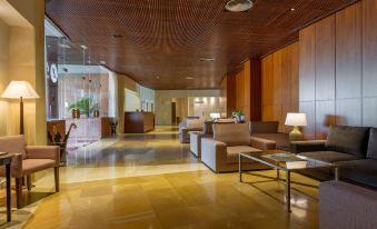 a modern hotel lobby with wooden ceiling , large windows , and various seating arrangements , including couches , chairs , and tables at Exe Layos Golf