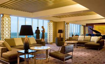 a modern hotel lobby with various seating options , including couches and chairs , and a view of the ocean at Novotel Bangka - Hotel & Convention Centre