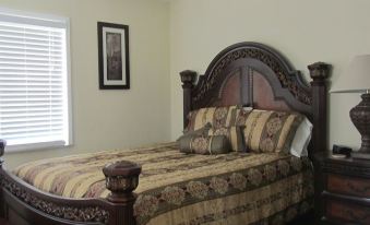 a large wooden bed with a floral comforter in a bedroom with a window and blinds at Kings Point