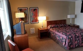 a hotel room with a bed , nightstand , and lamps , as well as a television on the left side of the room at Wine Valley Inn