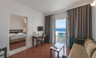 a hotel room with a bed , a tv , and a door leading to a balcony overlooking the ocean at Saint George Hotel