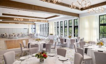 a large dining room with white tables and chairs , a chandelier , and a window overlooking the outdoors at The Williams Inn